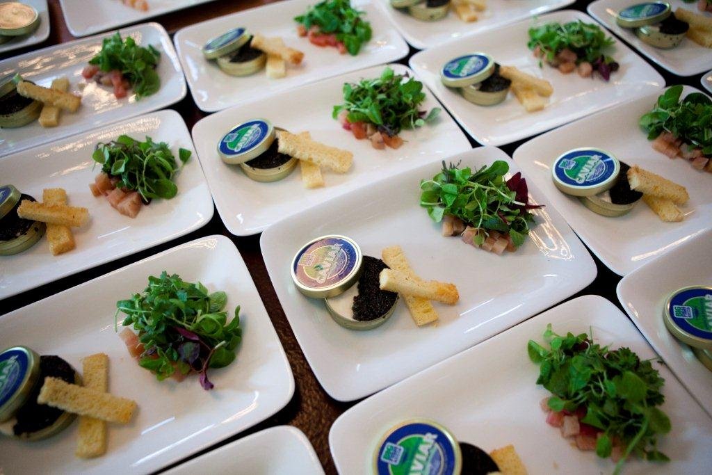 Elegant plated appetizers featuring caviar, fresh microgreens, and toasted breadsticks, arranged on white rectangular dishes for a sophisticated dining experience.